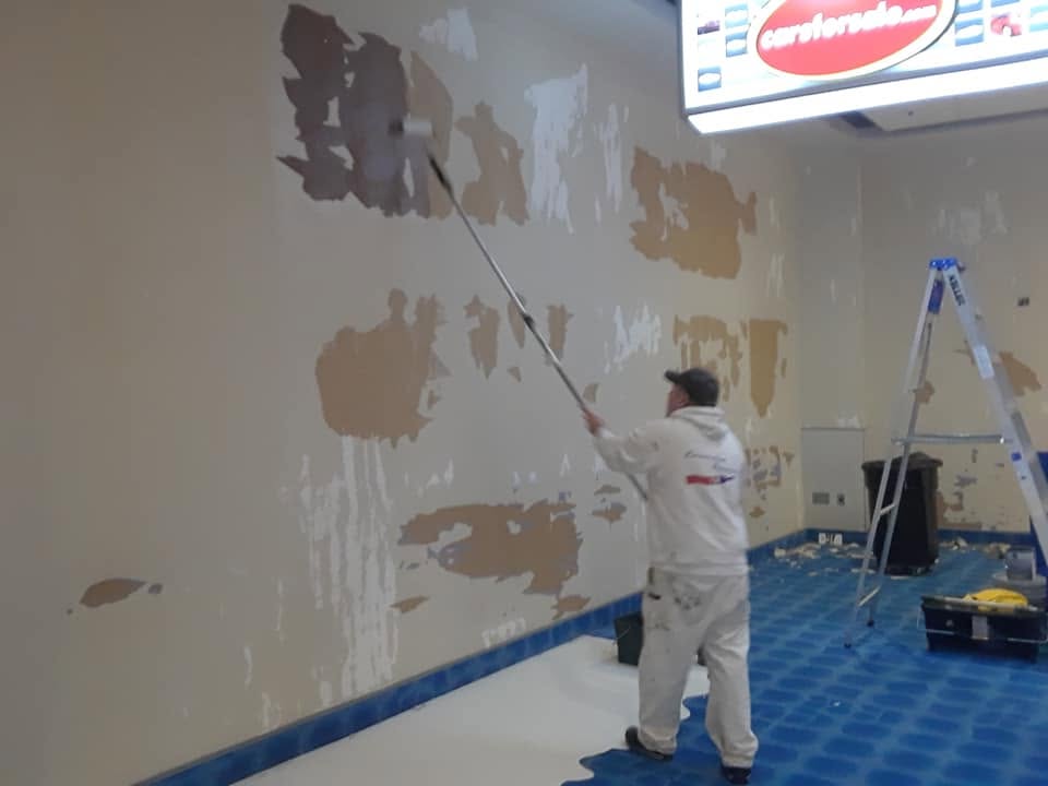 Cornerstone painter rolling fresh paint onto a repaired wall at the Denny Sanford Premier Center